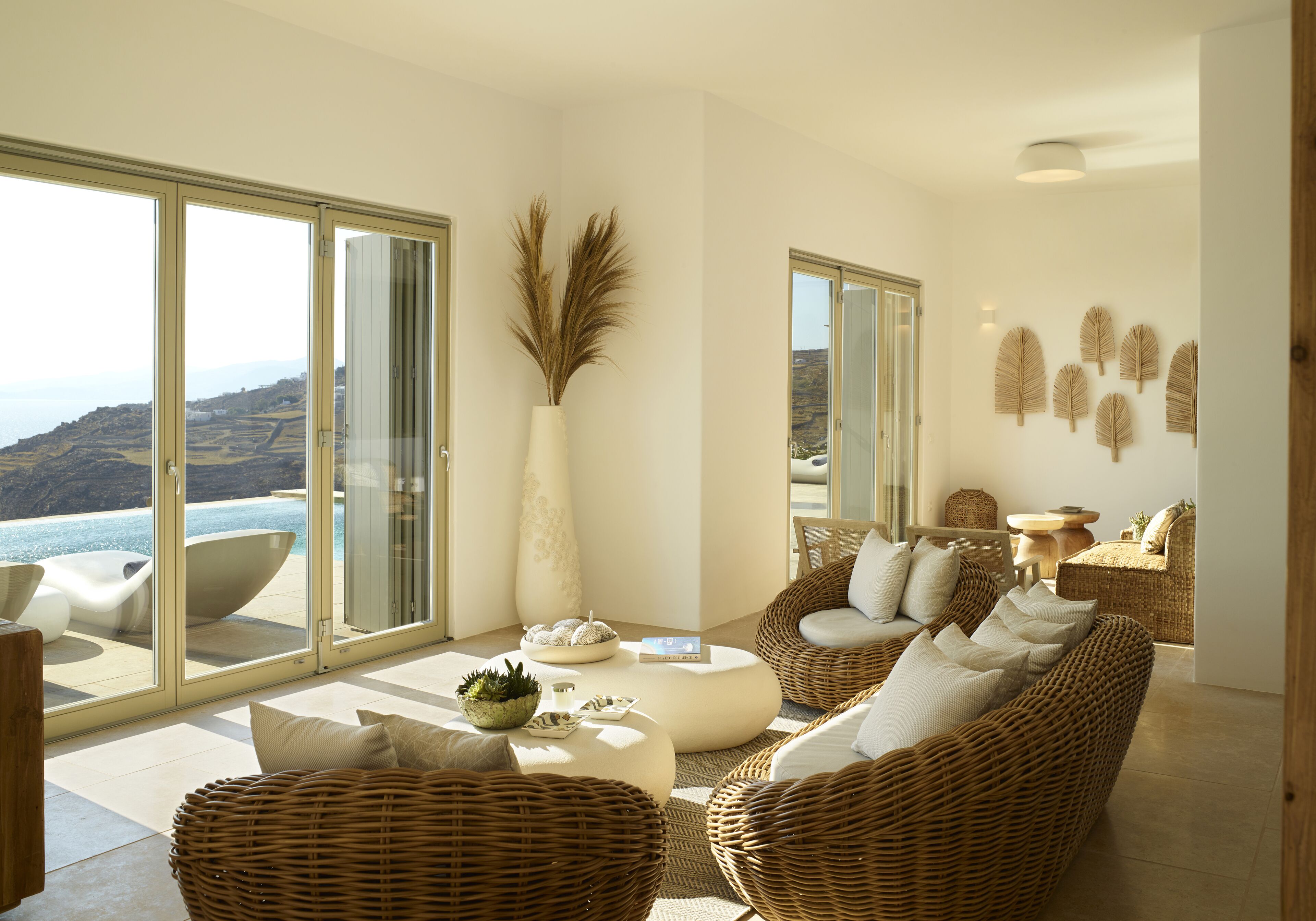 A modern living room with wicker furniture, a large vase, and a view of the ocean.