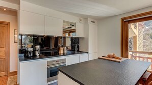 Una cucina moderna con mobili bianchi, un piano di lavoro nero e elettrodomestici in acciaio inossidabile.