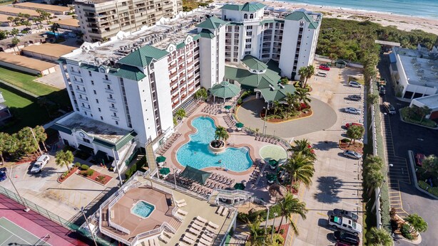 A hotel with multiple buildings, a swimming pool, and a tennis court. - Escape to Paradise: Stunning 2BR Oceanfront at The Resort on Cocoa Beach! (Cocoa Beach)