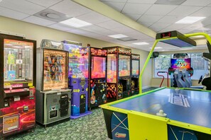 Eine Reihe von Spielautomaten mit einer digitalen Anzeigetafel und einem Billardtisch im Vordergrund.