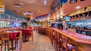 Un bar con una barra larga, sillas de madera y una variedad de botellas.
