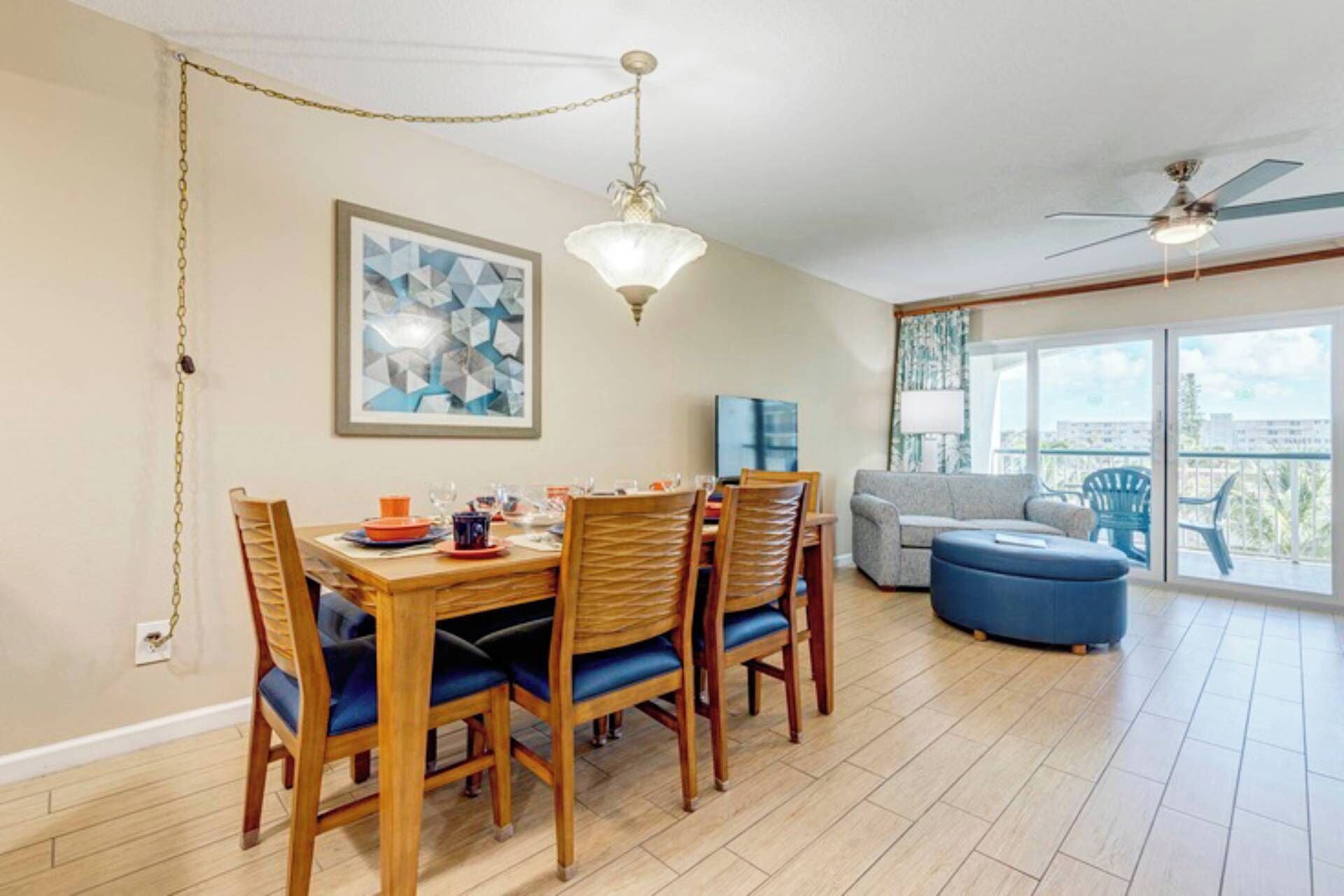 A dining area with a wooden table and chairs, a chandelier, and a painting on the wall.