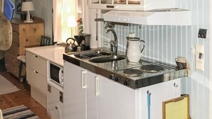 A compact kitchen with a sink, stove, and a small cabinet above the counter.
