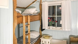 A bunk bed room with a window, a small table, and a chair.