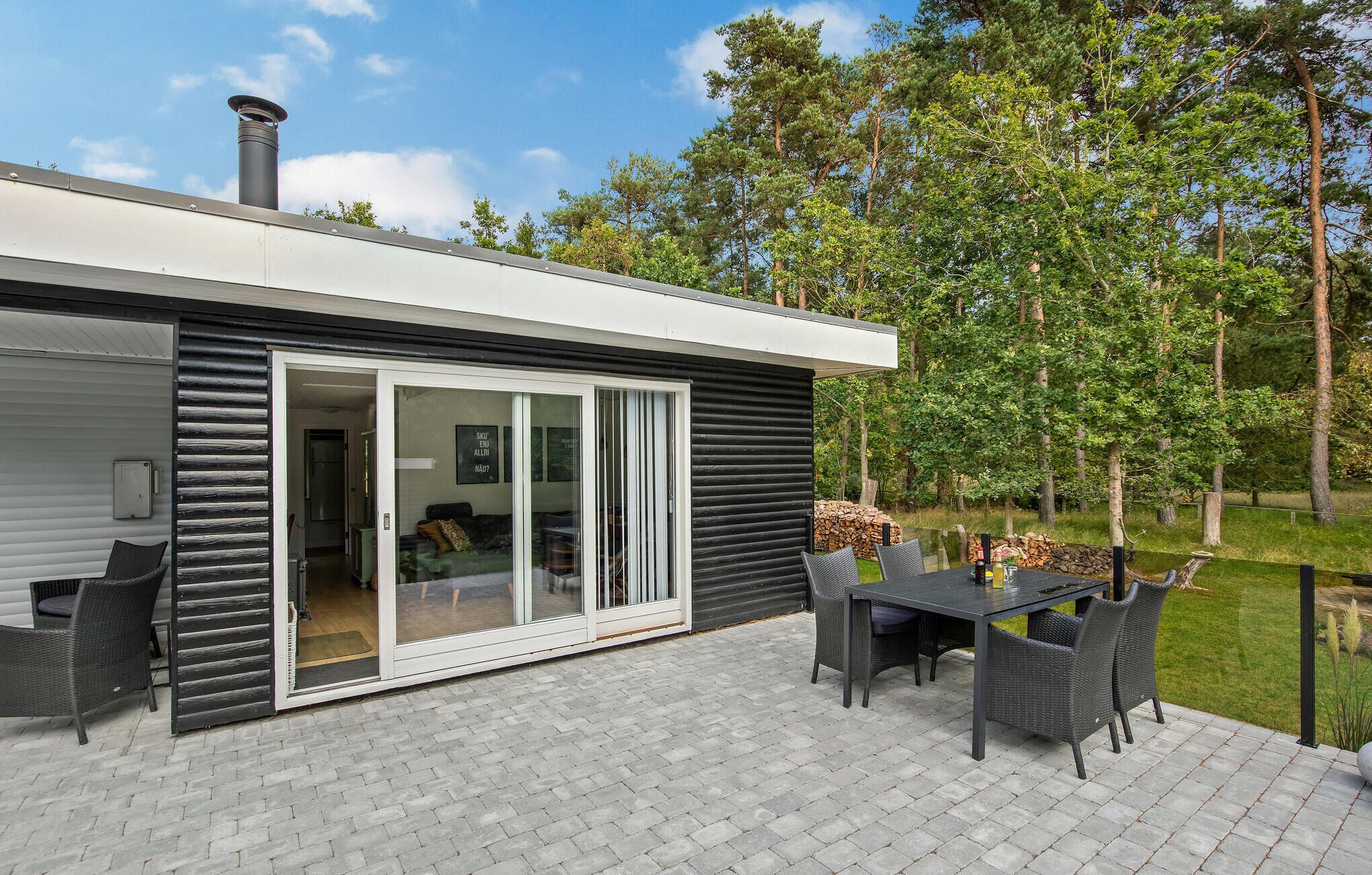 Une maison moderne dotée d’un patio comprenant une table et des chaises, une porte-fenêtre coulissante et une cheminée.