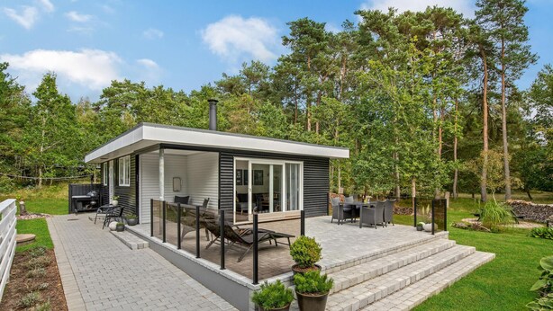 A modern outdoor patio area with a glass enclosure, outdoor furniture, and a small garden. - Beautiful home in Aakirkeby with WiFi (Aakirkeby)