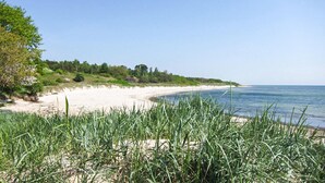 A beach with clear skies, sandy shore, and green vegetation. - Beautiful home in Aakirkeby with WiFi (Aakirkeby)