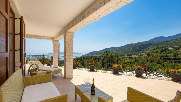 Una terrazza con mobili in vimini, una bottiglia di champagne e piante in vaso.