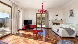 Un ampio soggiorno con un grande televisore, un lampadario rosso e un divano bianco.