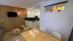 Un salon moderne avec un plancher en bois, une table à manger et un téléviseur fixé au mur.