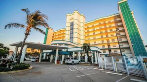 Een meerlaags hotel met een centraal atrium, een parkeerplaats en een hekpoort.