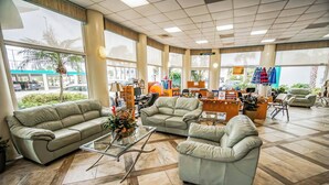 Een ruime lobby met een grote bank, een bijzettafeltje en een zithoek met een klein tafeltje en stoelen. Er zijn grote ramen met uitzicht op buiten.
