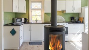 Una cucina moderna con mobili bianchi, un forno a microonde, un fornello e una stufa a legna.