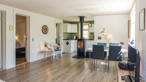 Una cucina moderna con stufa a legna, mobili bianchi e zona pranzo con tavolo e sedie.