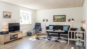 Un soggiorno con TV, poltrona in pelle, divano, tavolino da caffè e lampade decorative.