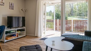 Un salon avec une télévision, une bibliothèque, une petite table et un canapé.