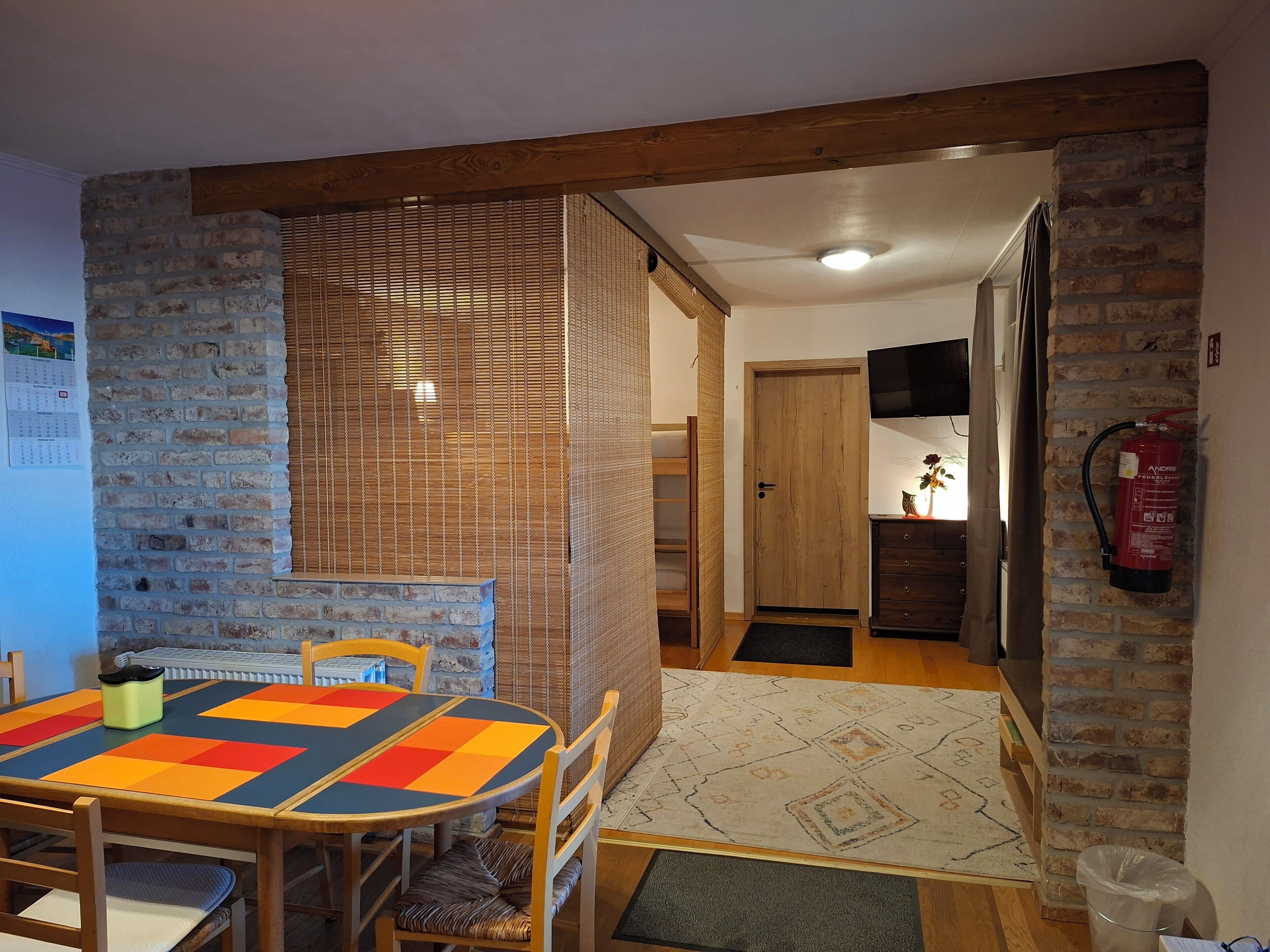 Een gezellige eethoek met een ronde tafel en stoelen, een bakstenen muur en een houten balk.
