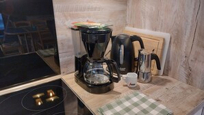 A kitchen with a coffee maker, kettle, and a checkered cloth on the counter.