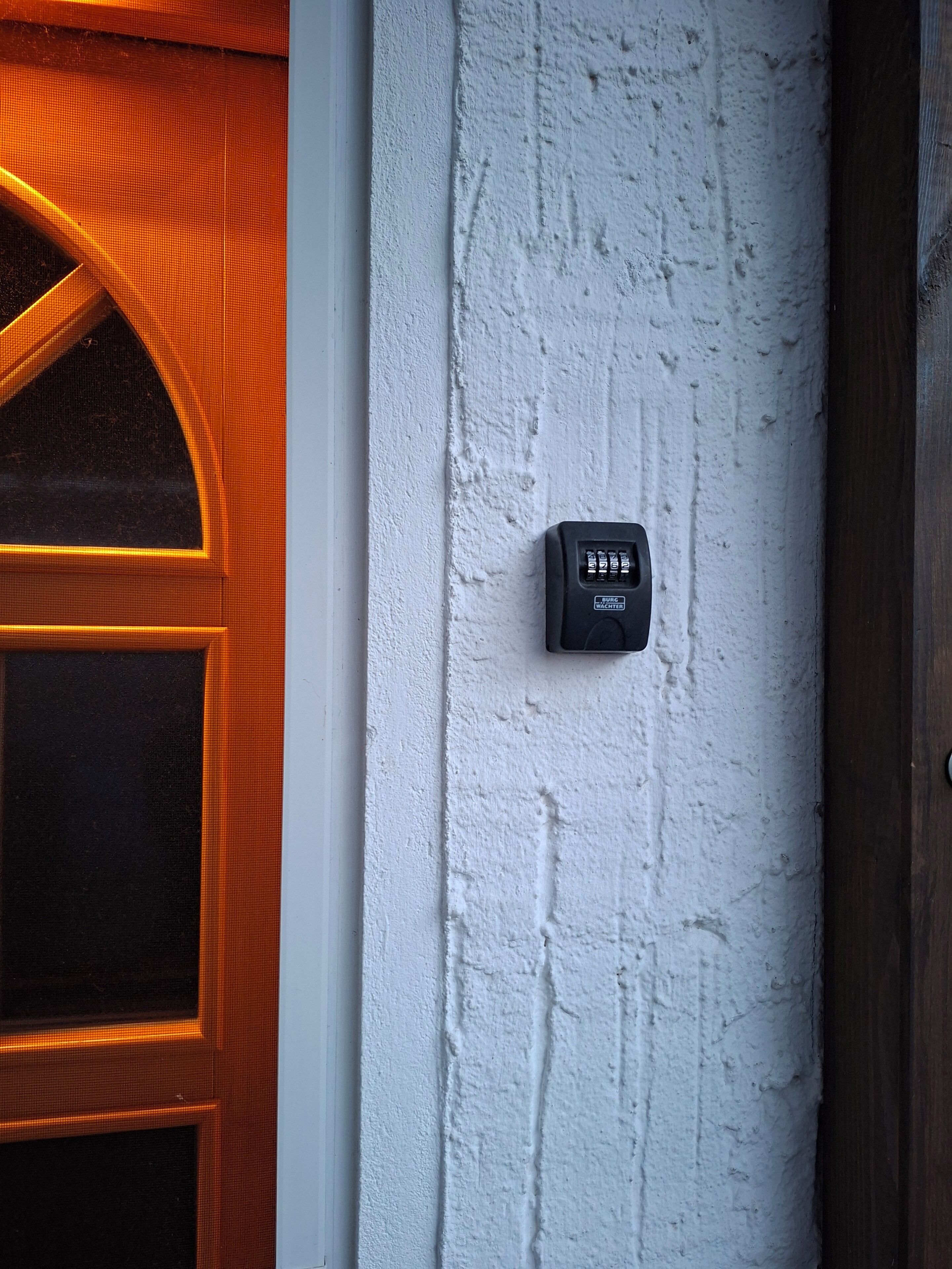 A door with a textured white wall and a security keypad.