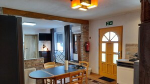 A dining area with a table and chairs, a kitchen with a dishwasher, and a door with an exit sign.