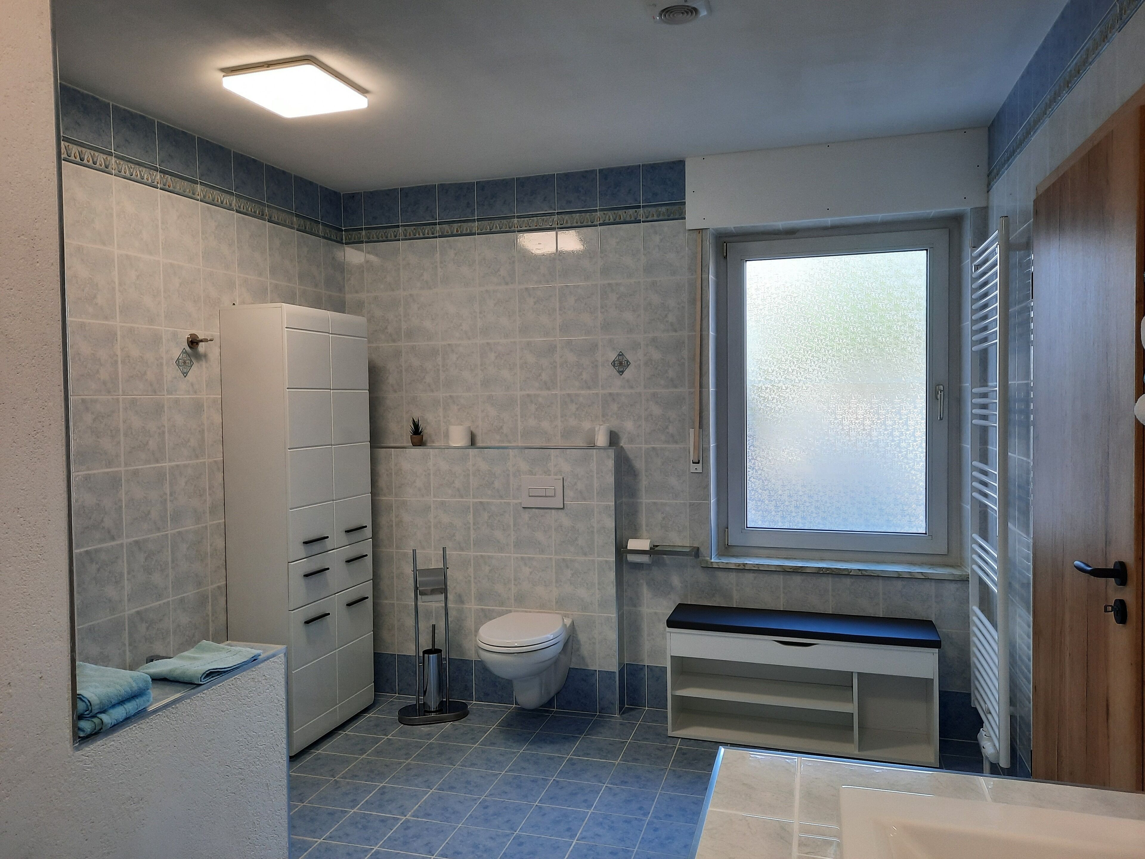 Ein Badezimmer mit Toilette, Waschbecken, Spiegel und Fenster.