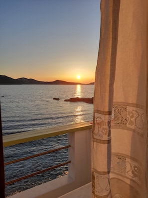 A balcony with a view of the sea at sunset.
