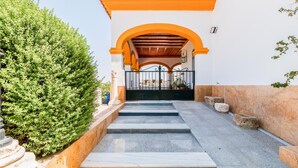 A staircase leading to an arched entrance with a tiled floor and a metal gate.