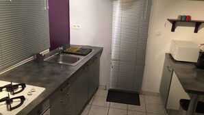 Een compacte keuken met een gasfornuis, spoelbak en een klein aanrecht.