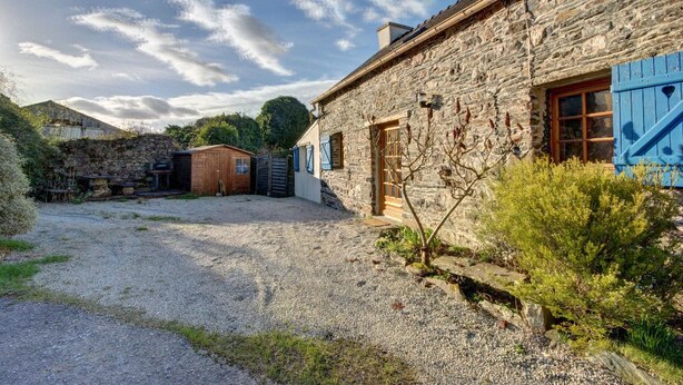 A stone building with a gravel driveway and a wooden door.