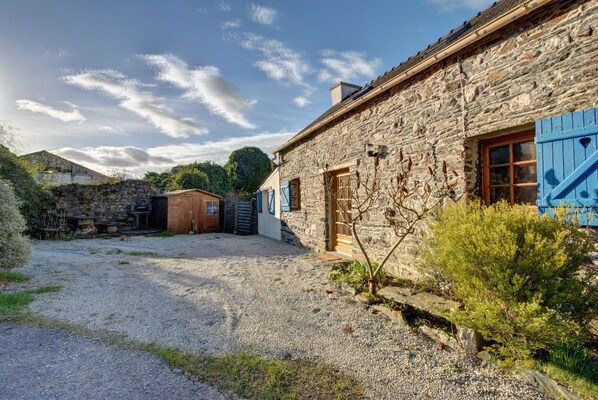 A stone building with a gravel driveway and a wooden door.
