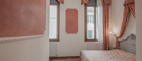 Un dormitorio con cama, candelabro y ventana con cortinas.