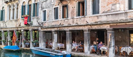 A historic building with outdoor seating and a canal view.