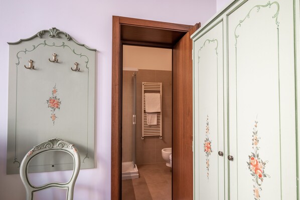 Un baño con ducha, inodoro y perchero para toallas.