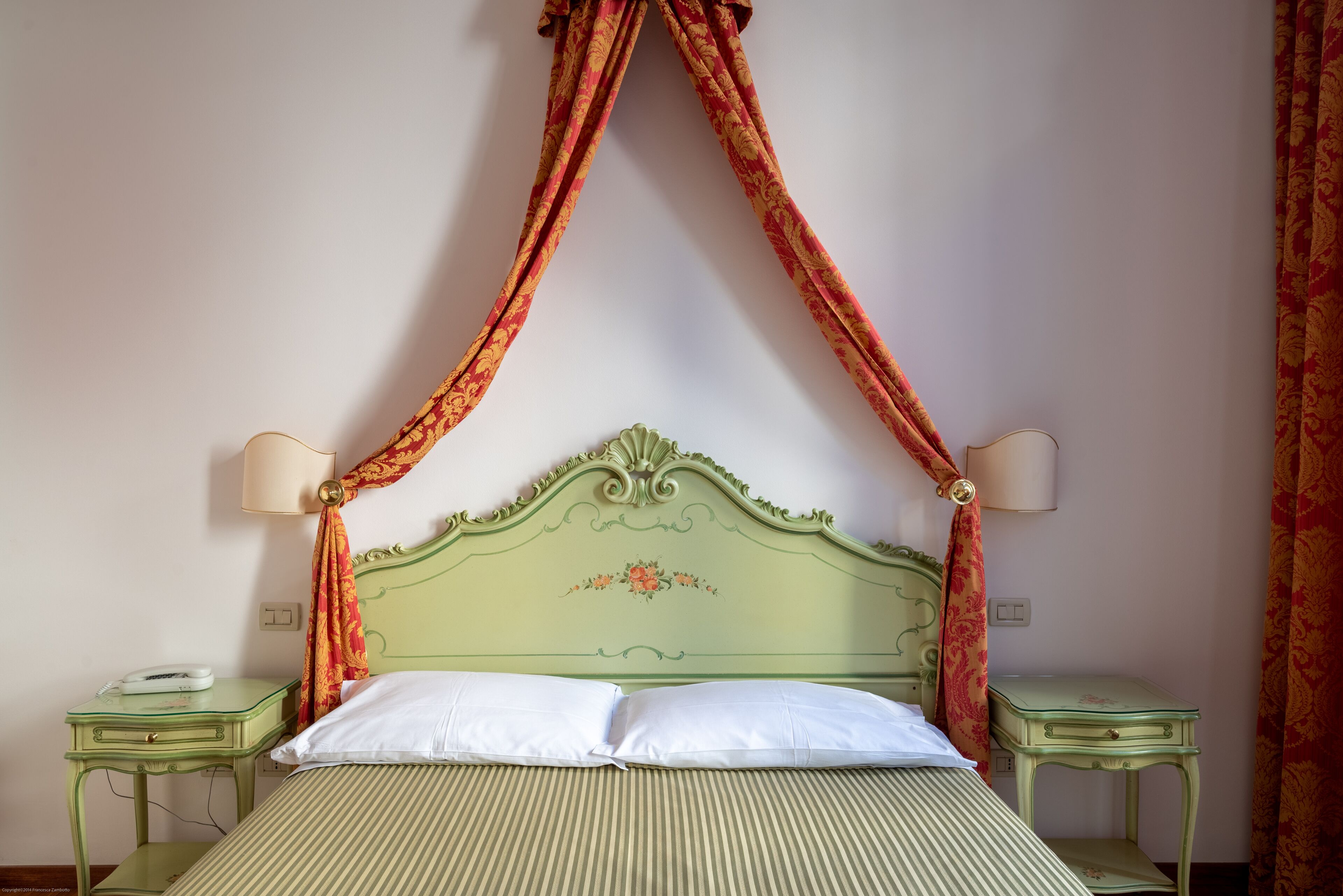 A bed with a green headboard, two bedside tables, and a canopy.