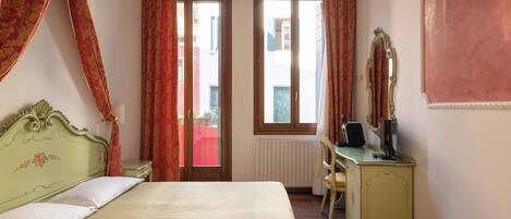 A bedroom with a bed, a desk, a chair, a mirror, and a window with curtains.