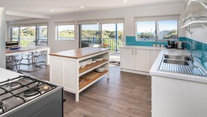 Uma cozinha moderna com armários brancos, bancada de madeira e vista para o exterior.