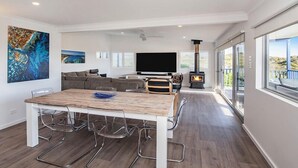 Uma sala de estar moderna com uma mesa de jantar de madeira, sofá, televisão e lareira.