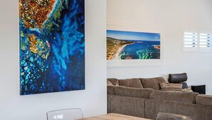 Uma sala de estar moderna com um sofá marrom, uma mesa de jantar de madeira e duas molduras na parede.