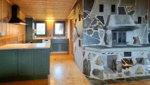 Una cocina con chimenea de piedra, armarios de madera y un ventanal grande.