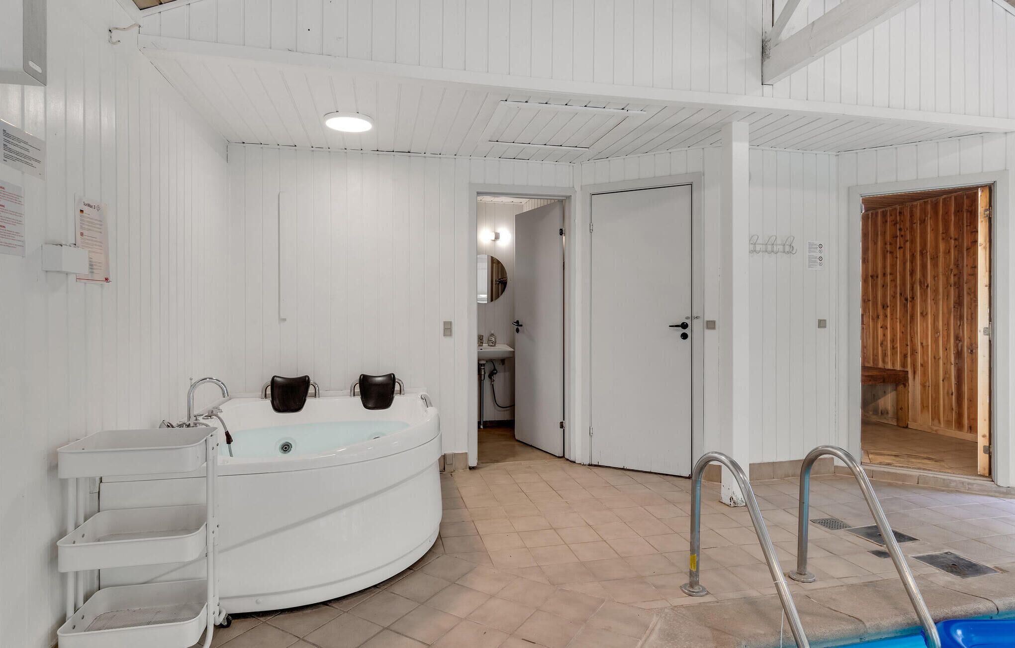 A spa area with a large bathtub, a sink, and a shower. There are three chairs and a small sink with a mirror.