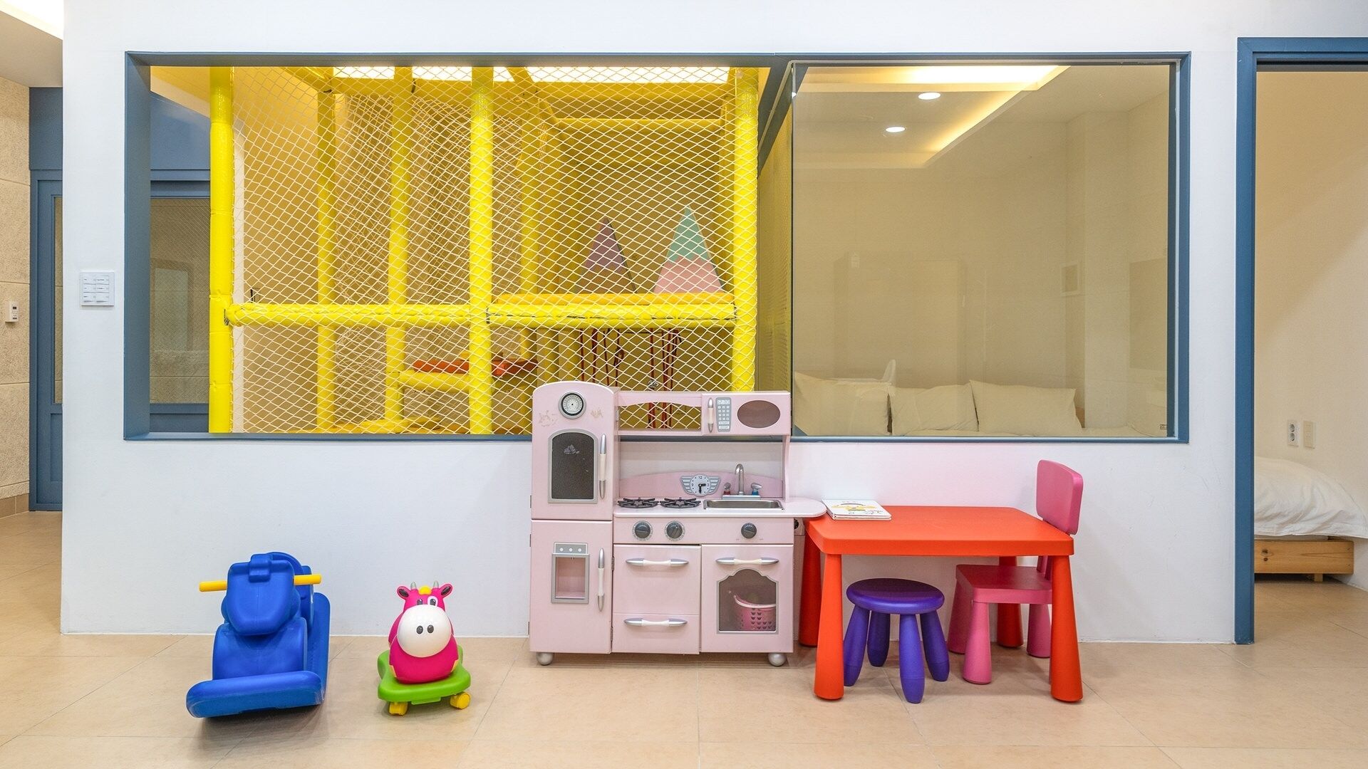 Ein Spielbereich für Kinder mit einer Spielküche, einem Spielzeugauto und einem Spielpferd.