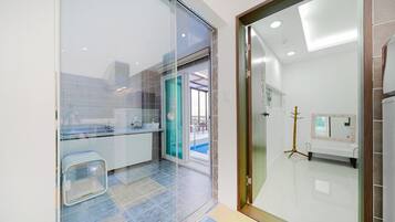 Casa de banho moderna com divisória de vidro, lavatório e sanita.