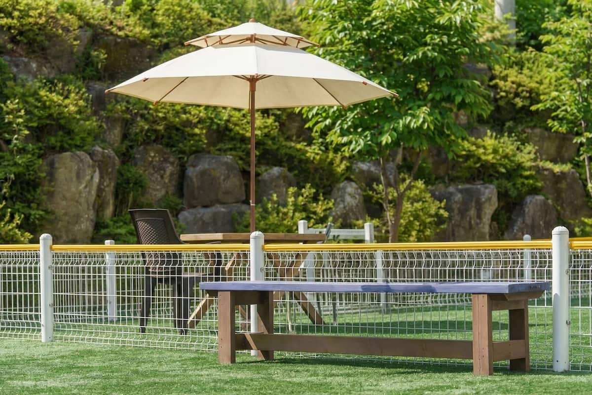 A fenced outdoor area with a picnic table and an umbrella.