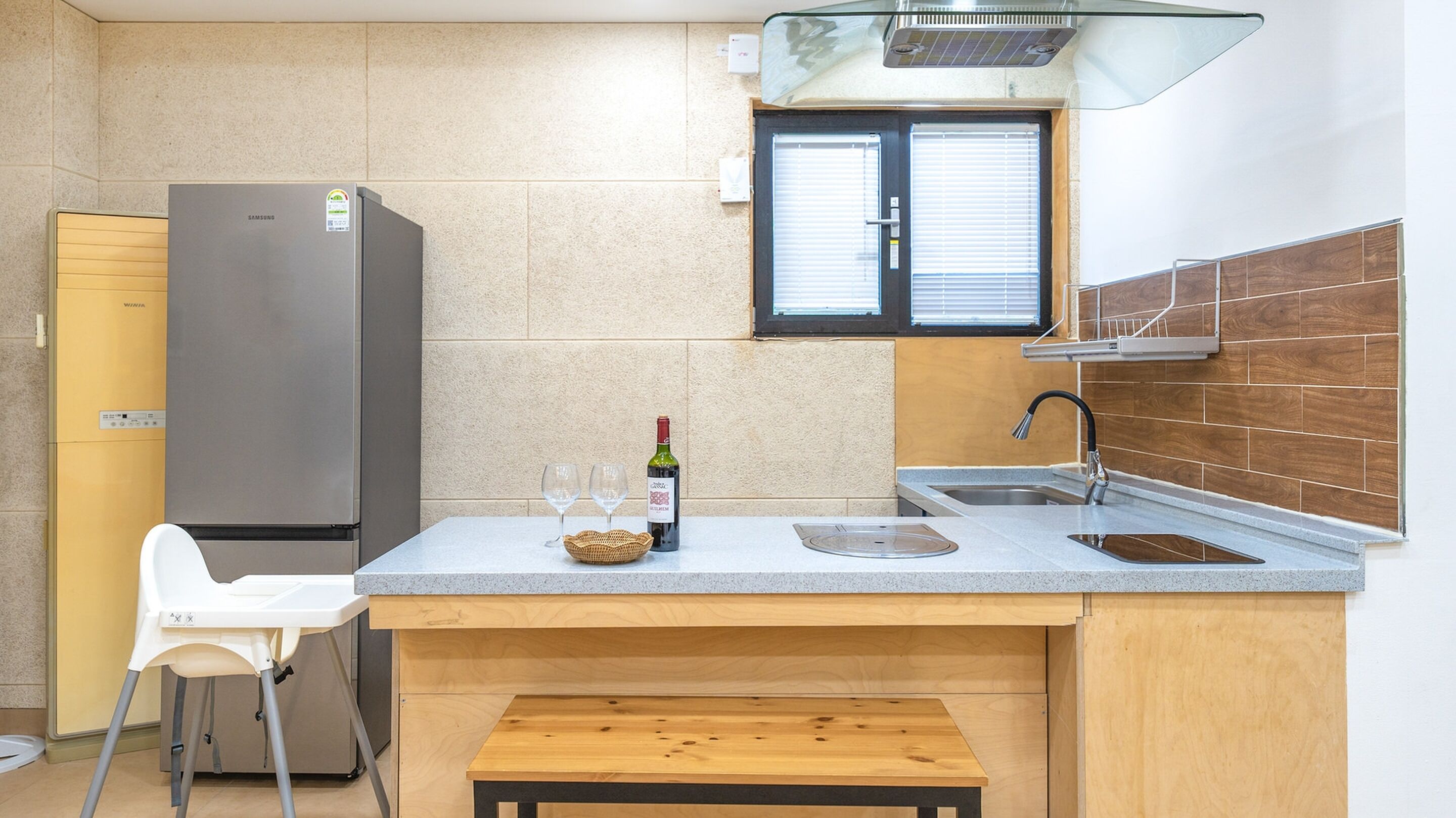 A compact kitchen with a built-in refrigerator, a sink, and a small wooden table.