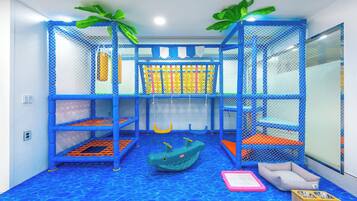 A play area with a blue net structure, a slide, a small boat, and a soft play mat.