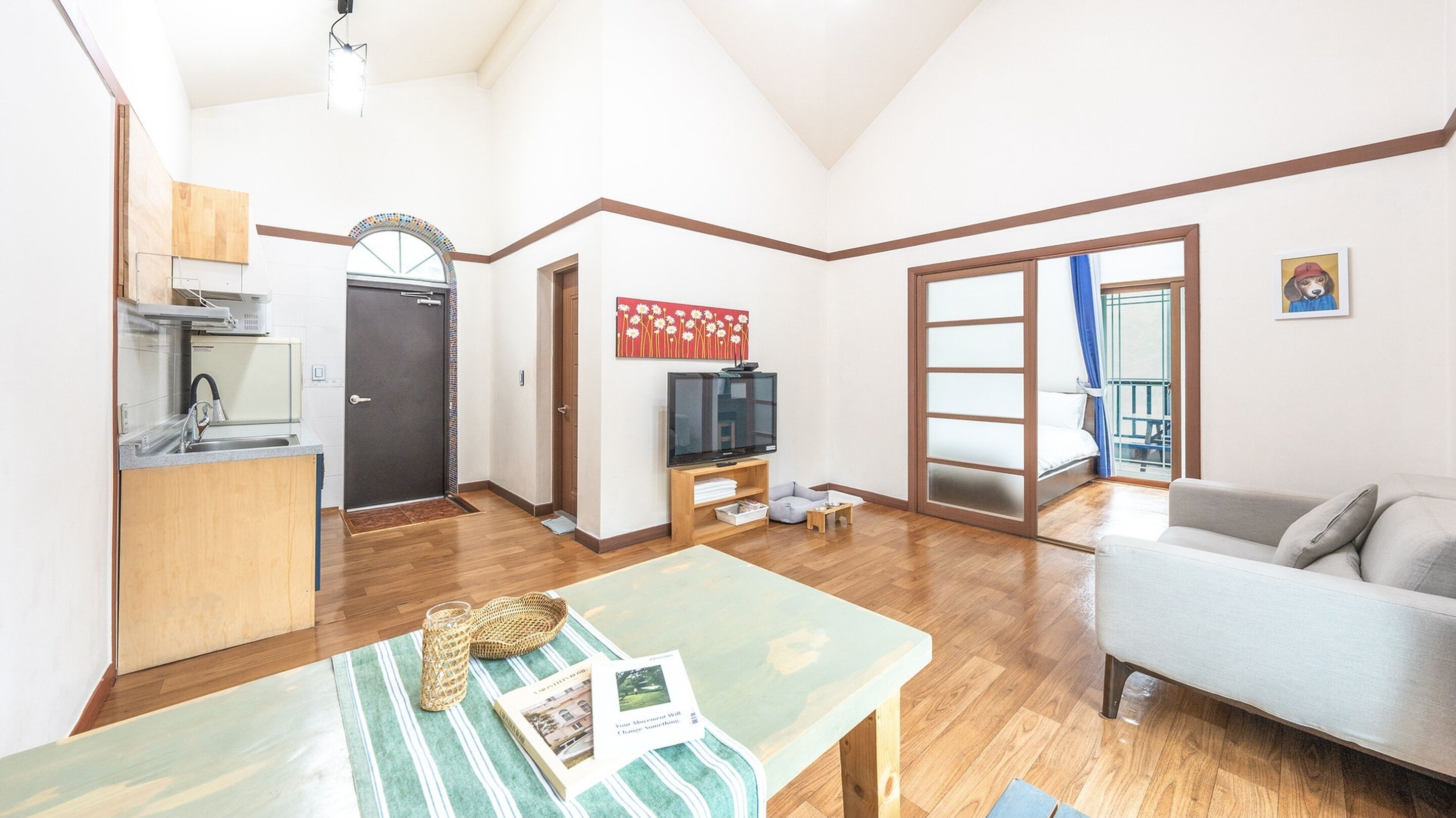 Un espacio habitable compacto con kitchenette, comedor, sofá y televisor.
