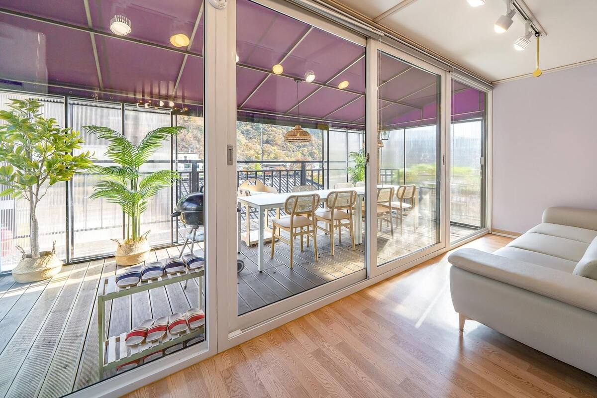 A modern living room with a sliding glass door leading to a balcony with outdoor furniture and a grill.