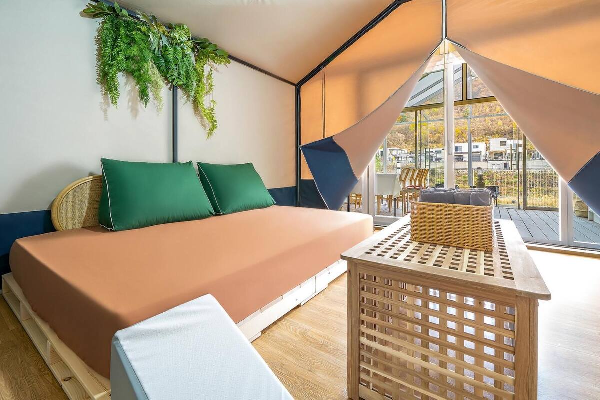 A modern room with a bed, a small table, and a view of the outside.