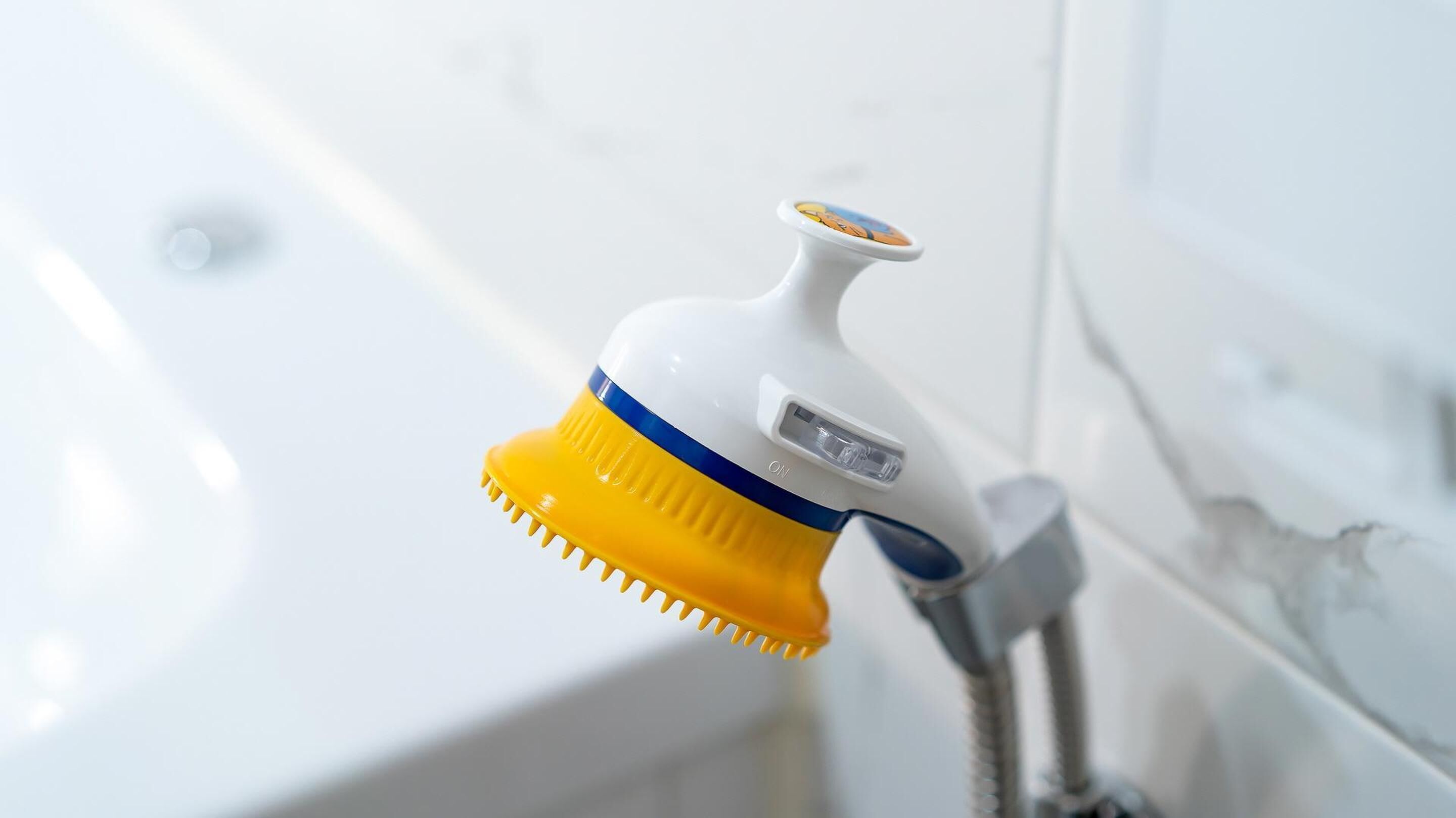 Un baño con un lavamanos blanco y un portalápices amarillo y azul montado en la pared.