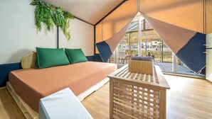 Una habitación con cama, una planta colgante, una mesa y vistas al exterior.